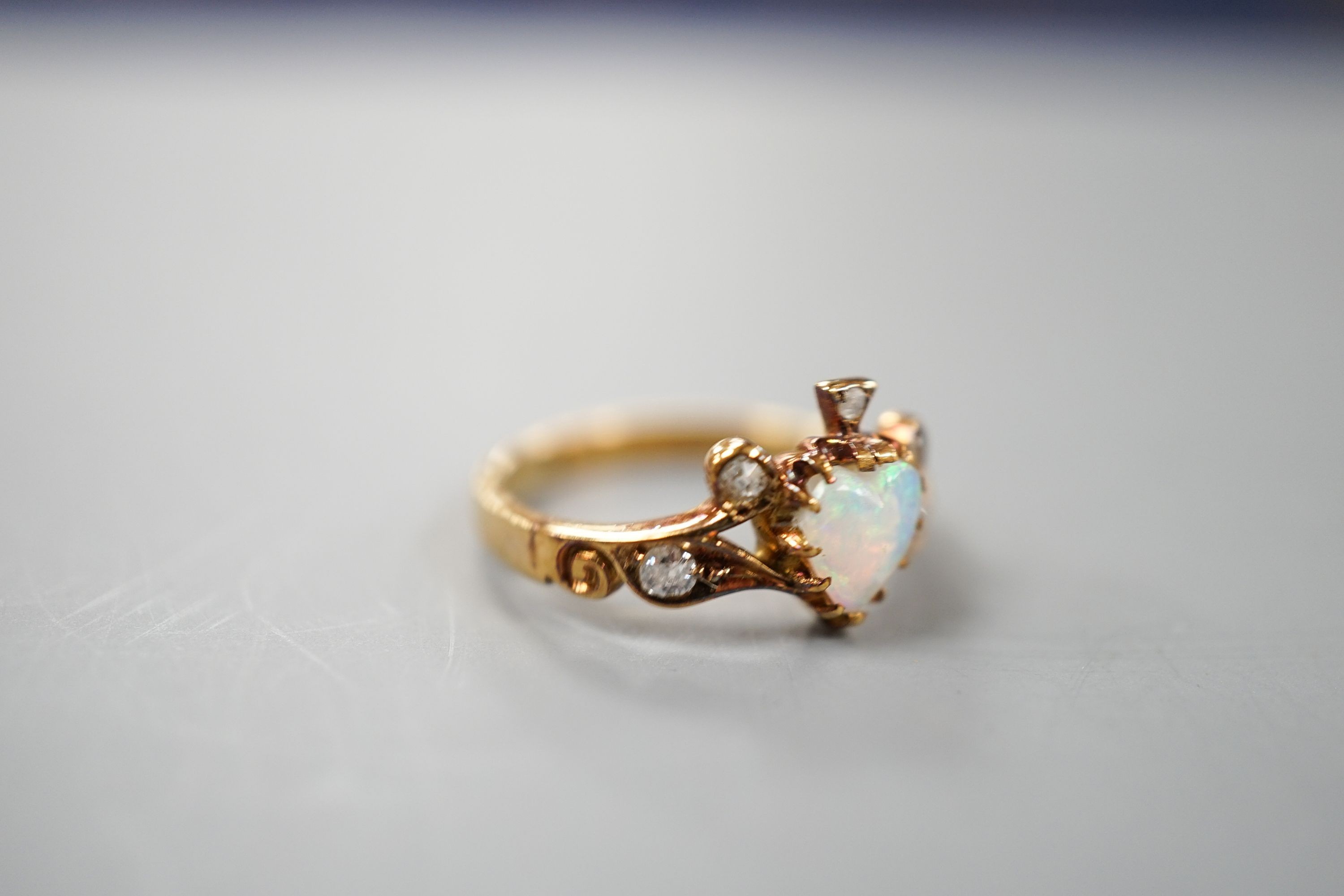 A late Victorian 18ct gold, heart shaped white opal and five stone diamond chip set dress ring, size I, gross weight 2.6 grams.